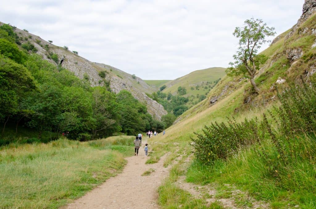 A trail between hills with people walking.