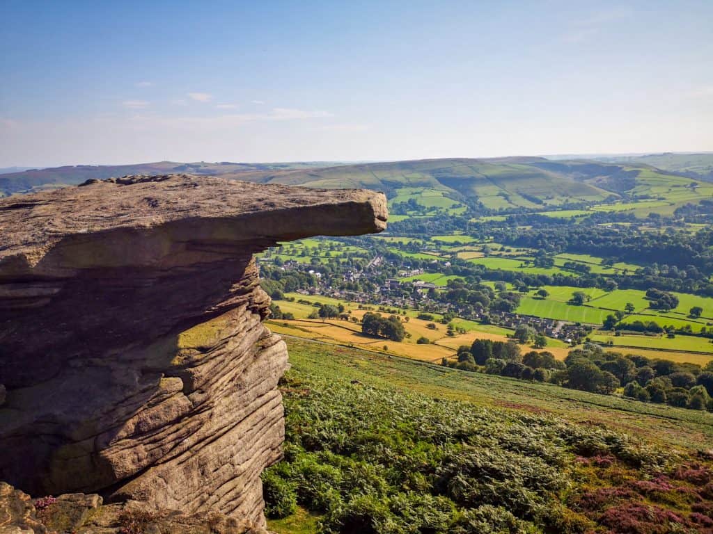 Rock formation with meadows and hills - Bramford Edge is among the best Peak District walks.