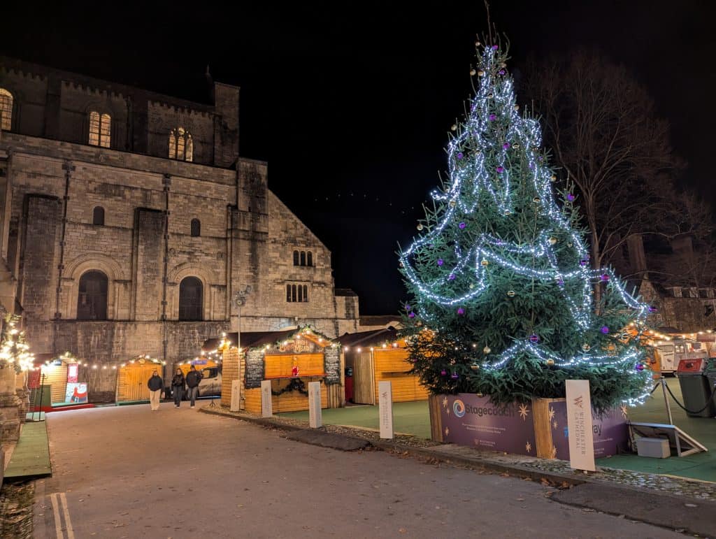 Winchester Cathedral Christmas market at night with the Christmas tree.