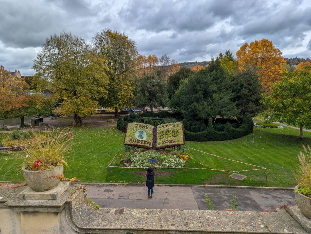 View at park in autumn with trees and big book made of flowers, visiting parks is one of the best things to do in Bath for couples.