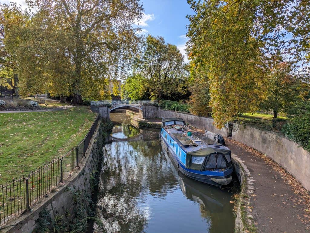 A trail around the river with boats and trees with colourful leaves. River walks are one of the best things to do in Bath for couples.
