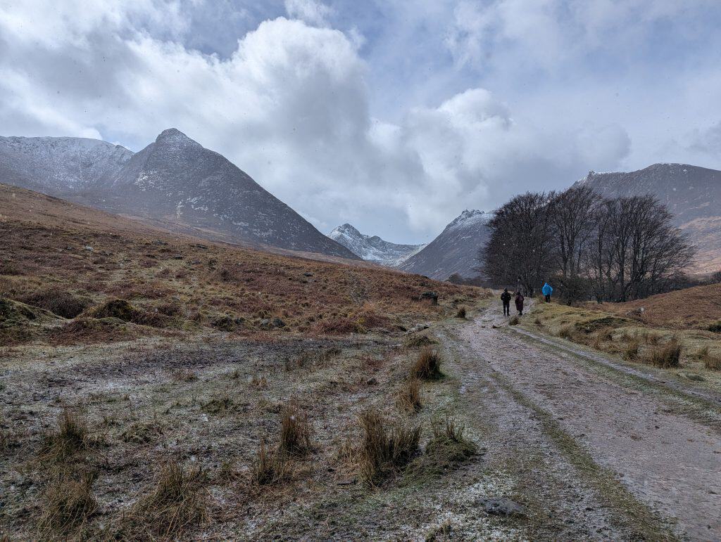 Glen Sannox with snowy mountains and people walking.